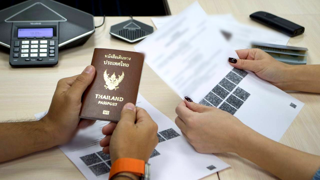 A Workmigration specialist hands a client a work permit and a foreign employee's passport